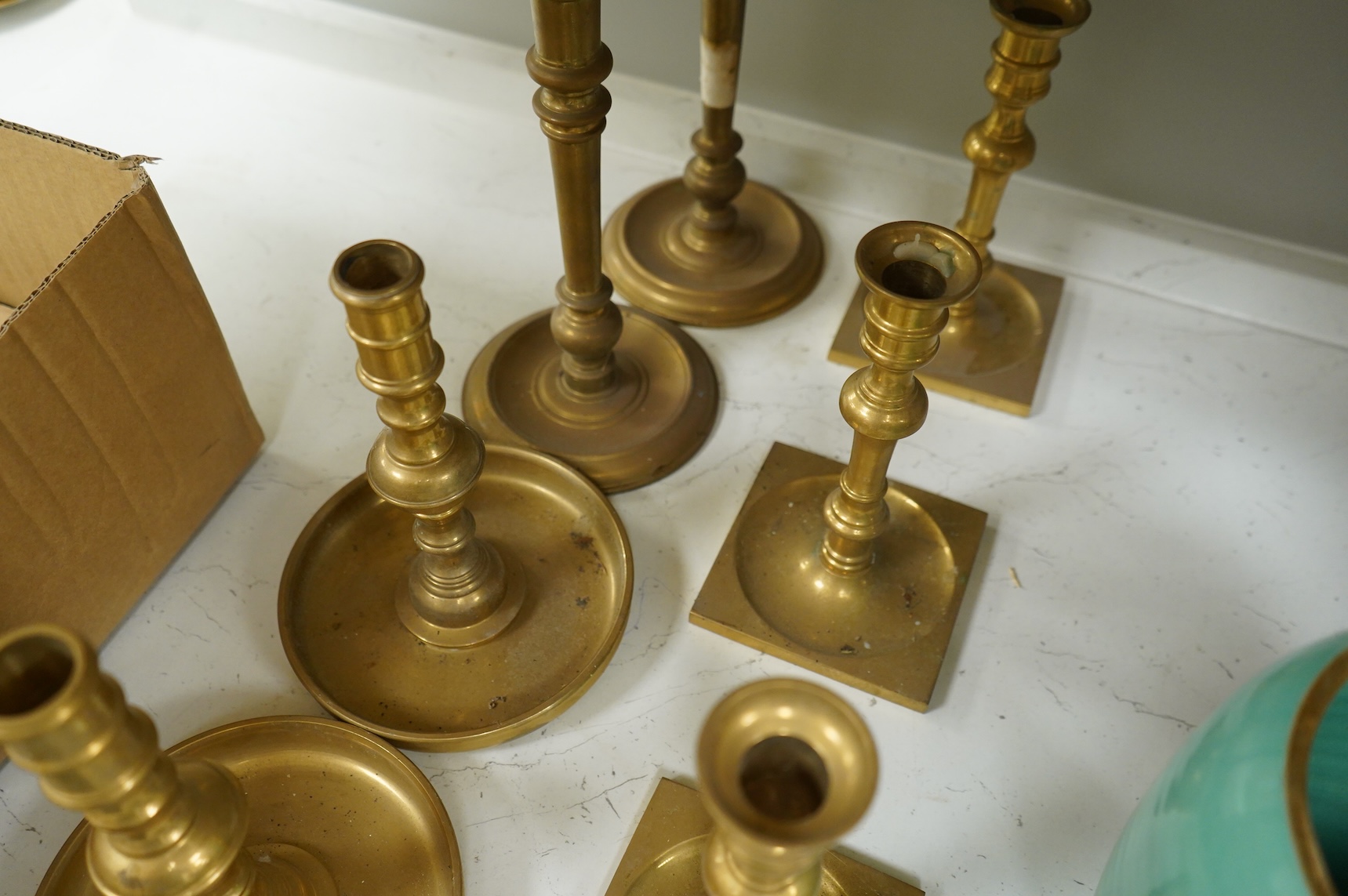 Two fire marks and a collection of brass candlesticks, tallest 25.5cm